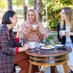 Delighted diverse women drinking coffee